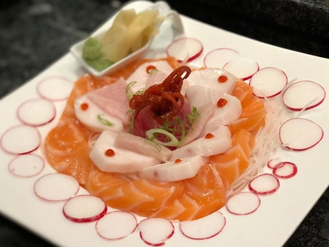 Thin slices of salmon and white fish arranged over radish rounds.
