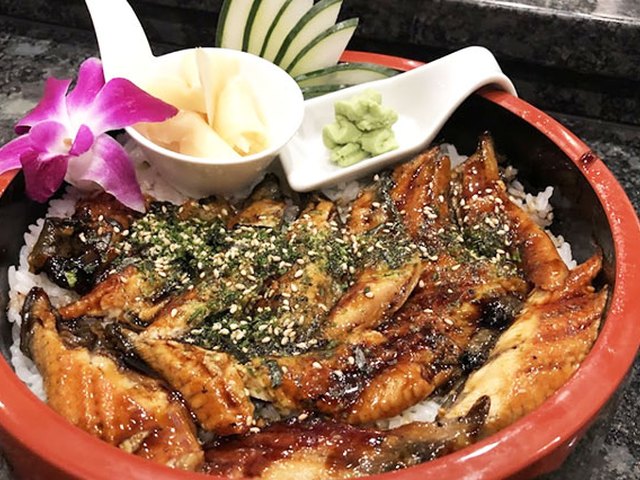 Grilled eel over rice in a red lacquer bowl.