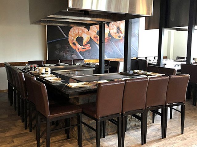 Hakata's dining room: hibachi grill tables with high-back leather chairs under steel hoods.